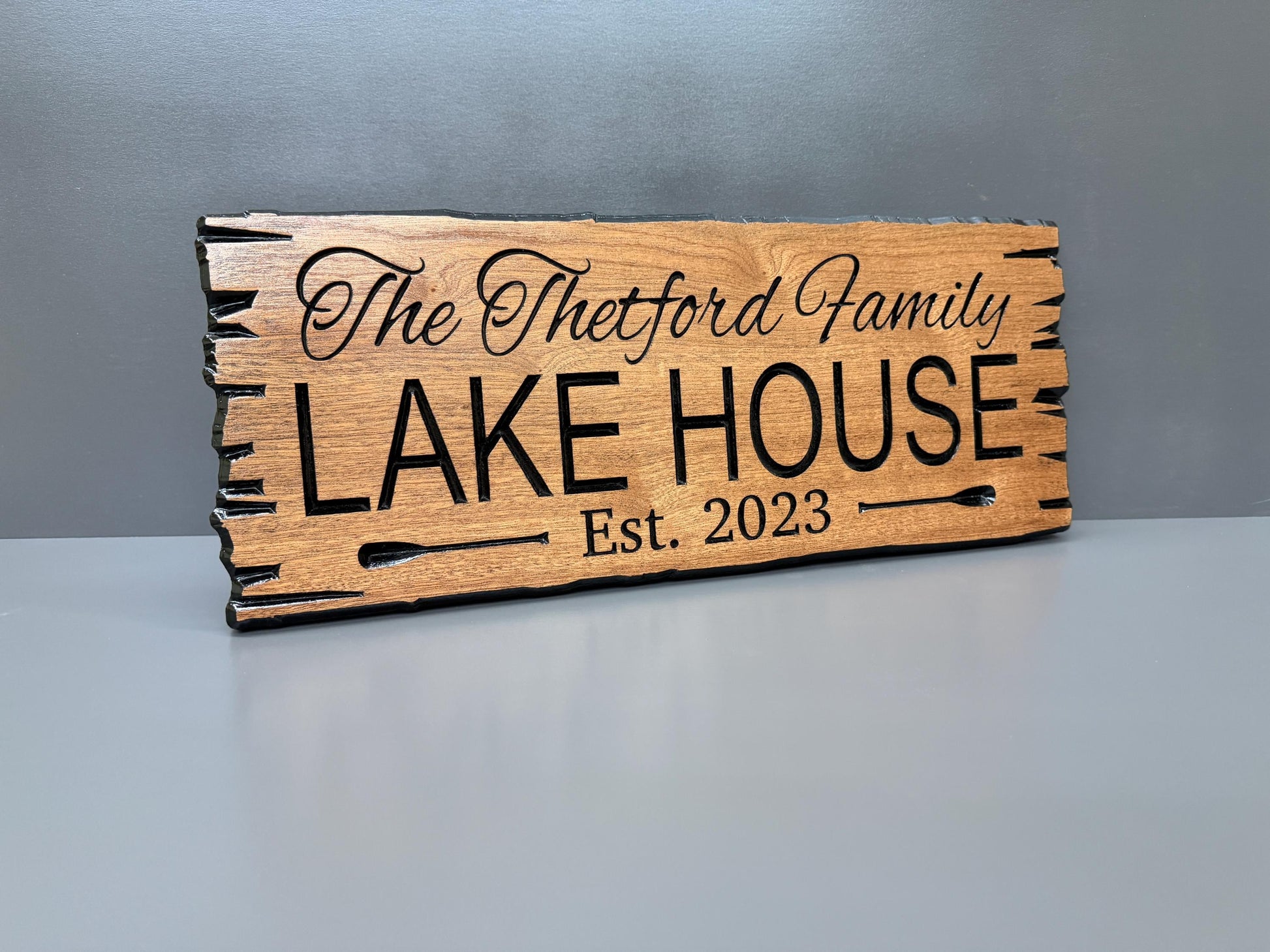 A wooden sign with the text "The Thetford Family Lake House Est. 2023" carved into it.