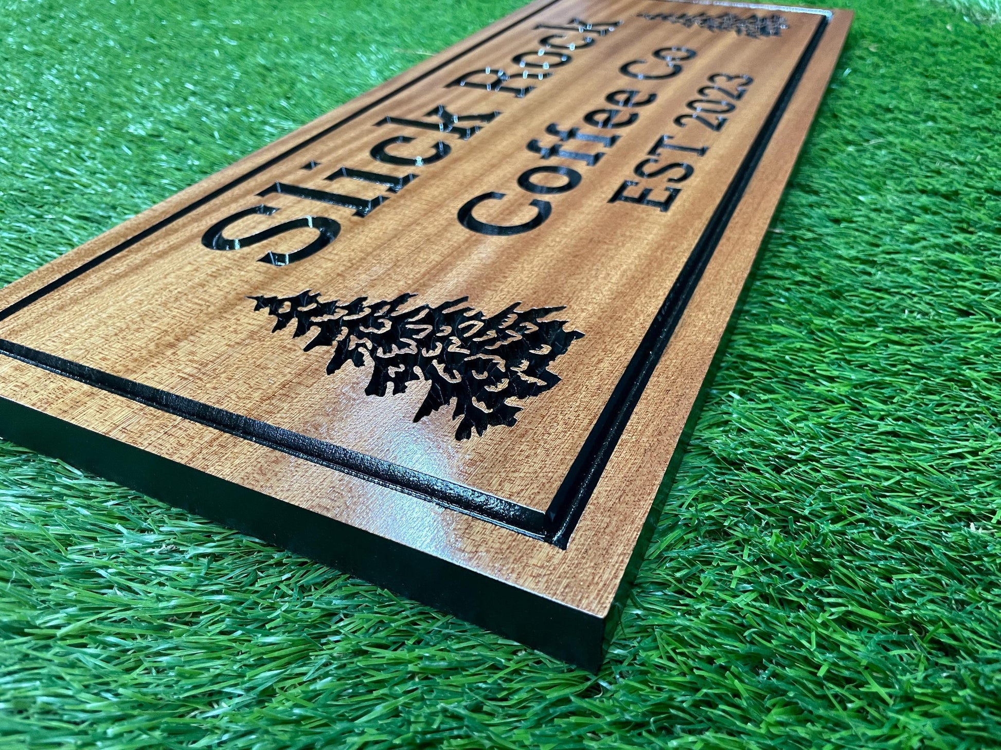A wooden sign with the text "Slick Rock Coffee Co" carved into it, placed on a green surface.