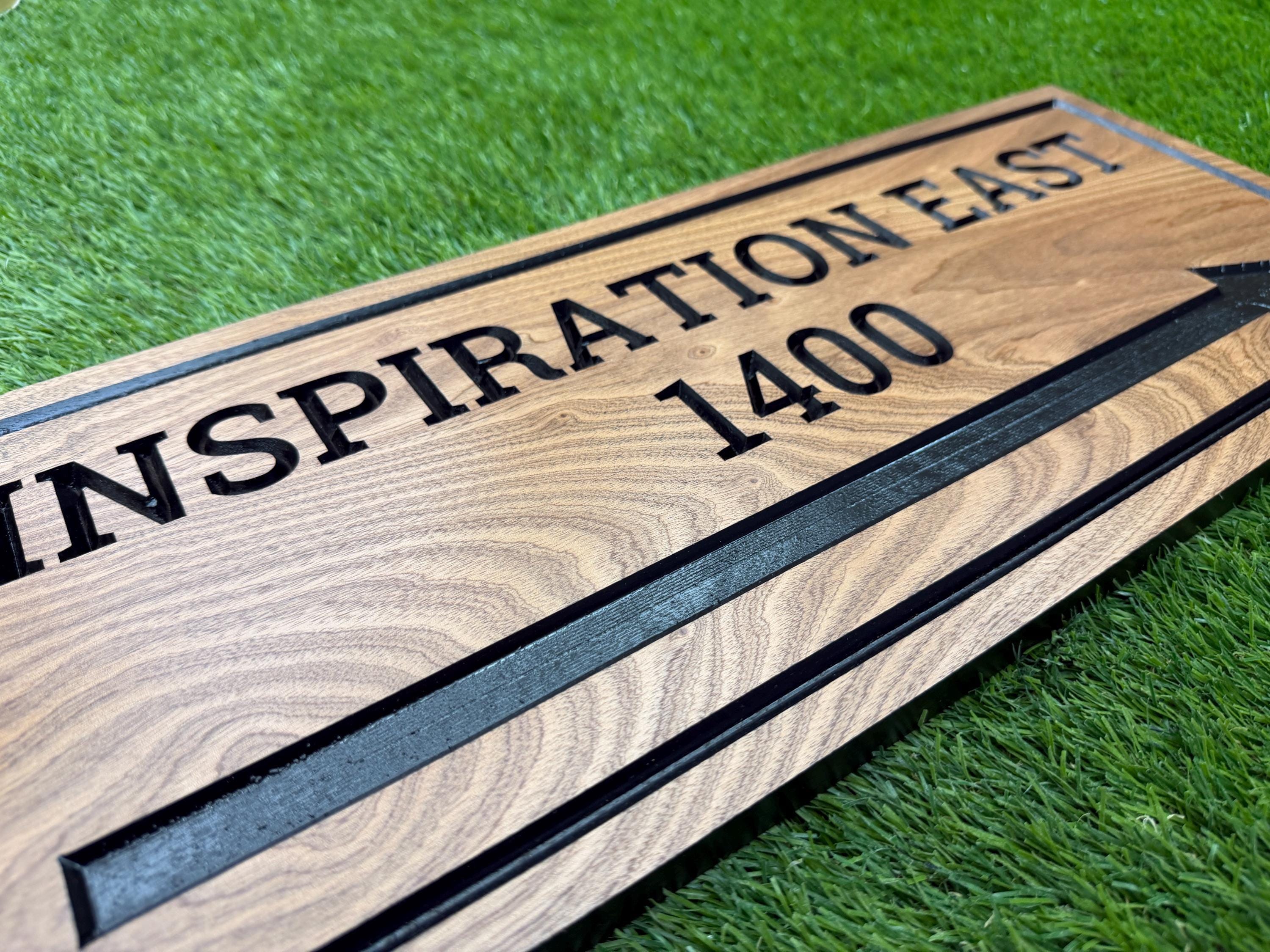 A wooden sign with the text "INSPIRATION EAST 1400" printed on it, placed on a grassy surface.