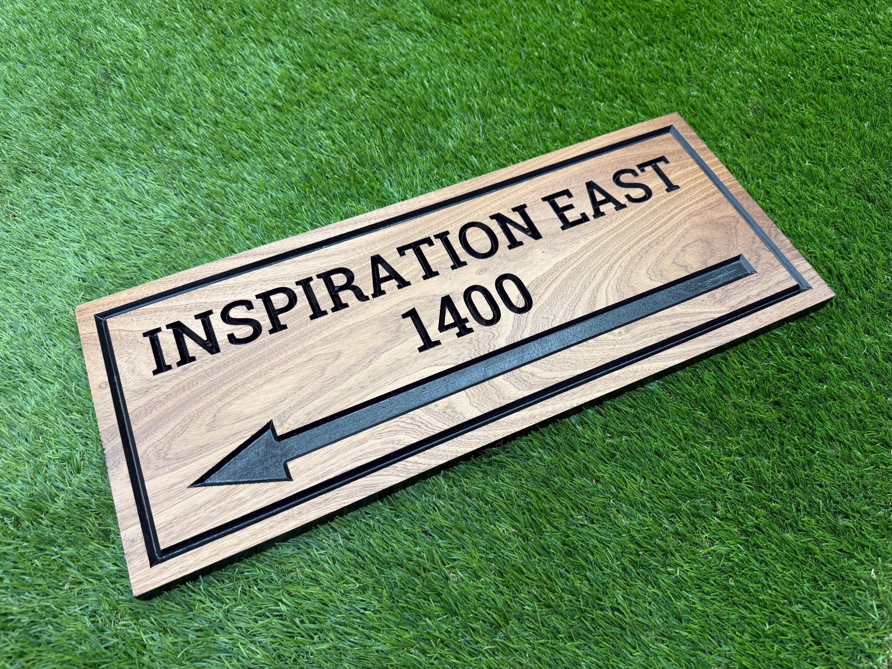 A wooden sign with an arrow pointing to the right, placed on a grassy surface.