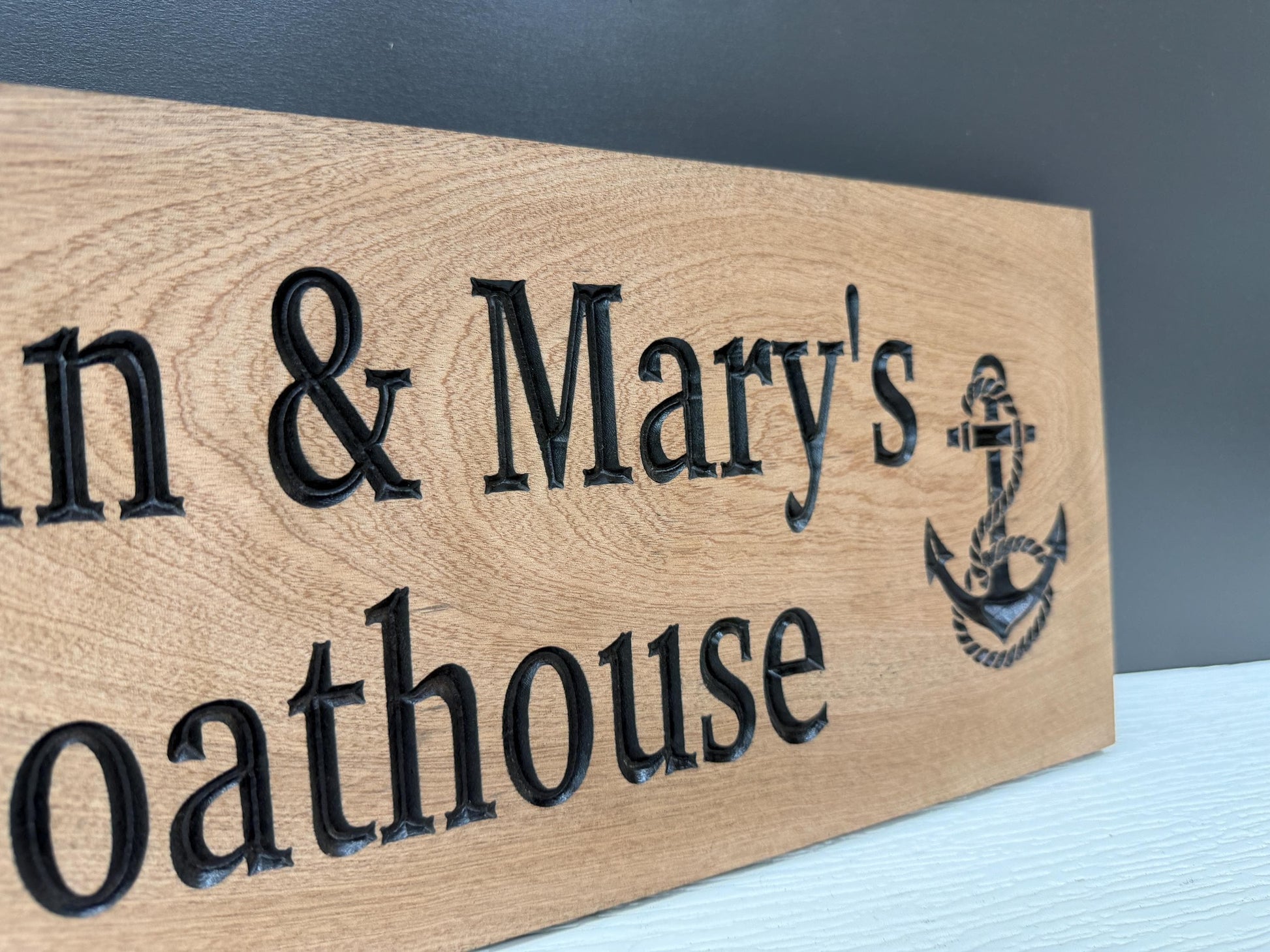 A wooden sign with the text "Oathhouse" and an anchor symbol, indicating the name of a houseboat.