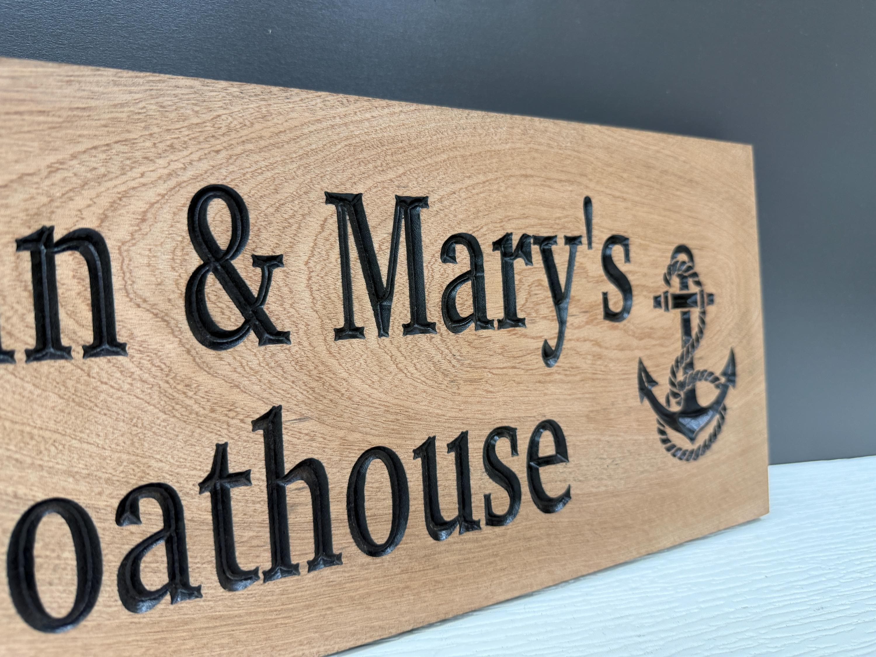 A wooden sign with the text "Oathhouse" and an anchor symbol, indicating the name of a houseboat.