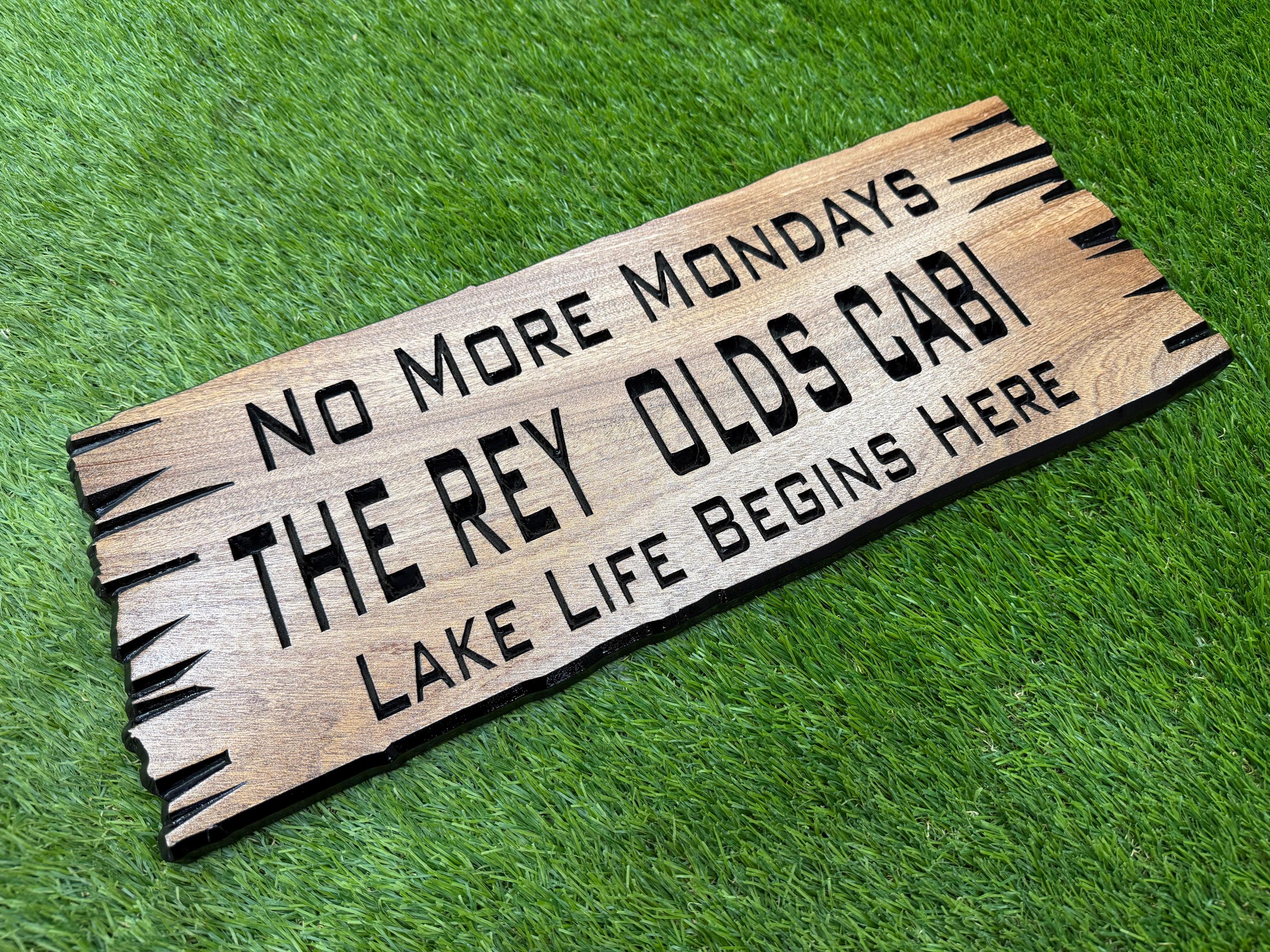 A wooden sign with text on it, placed on a grassy surface.