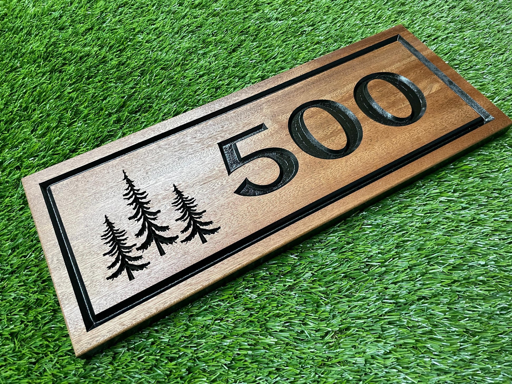 A wooden sign with the number "500" carved into it, placed on a grassy surface.