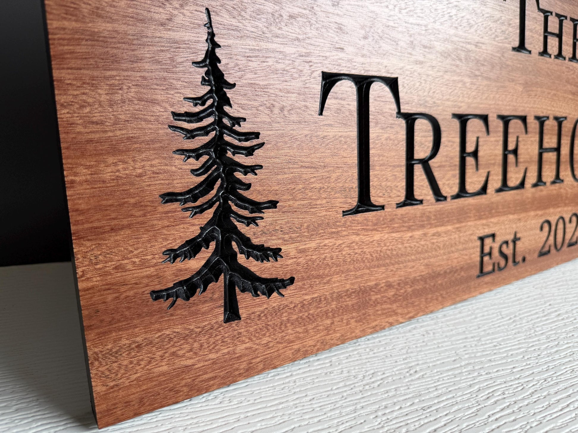a wooden sign with a carved tree design and text.