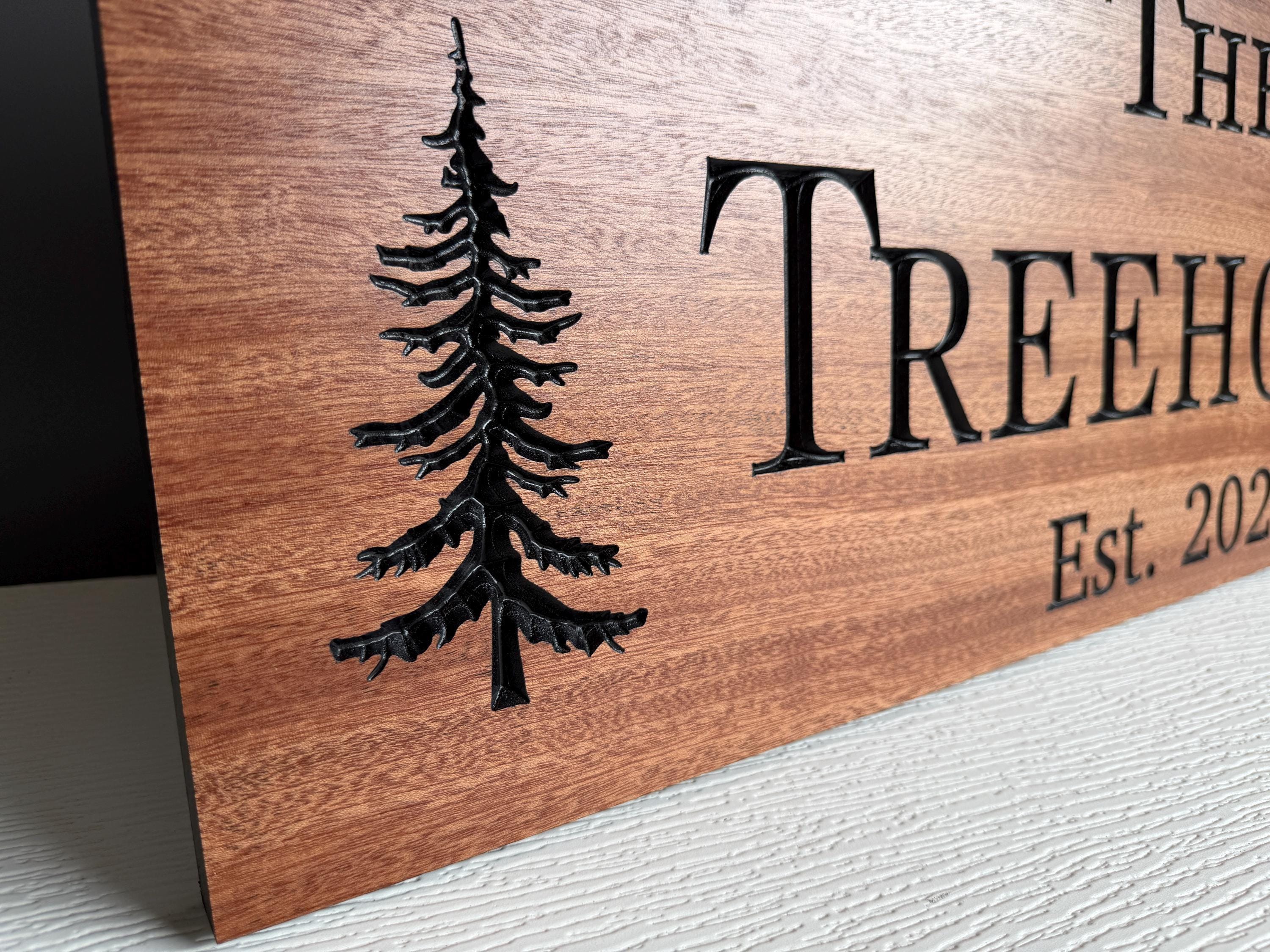 a wooden sign with a carved tree design and text.