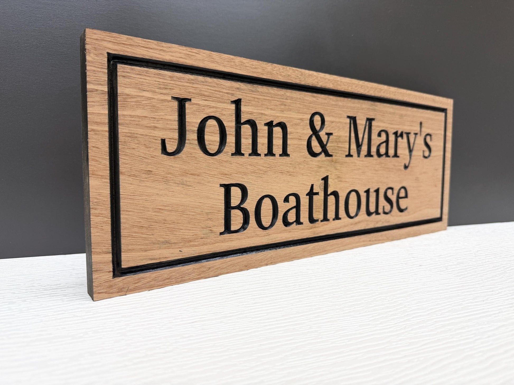 A wooden sign with the text "John & Mary's Boathouse" carved into it.