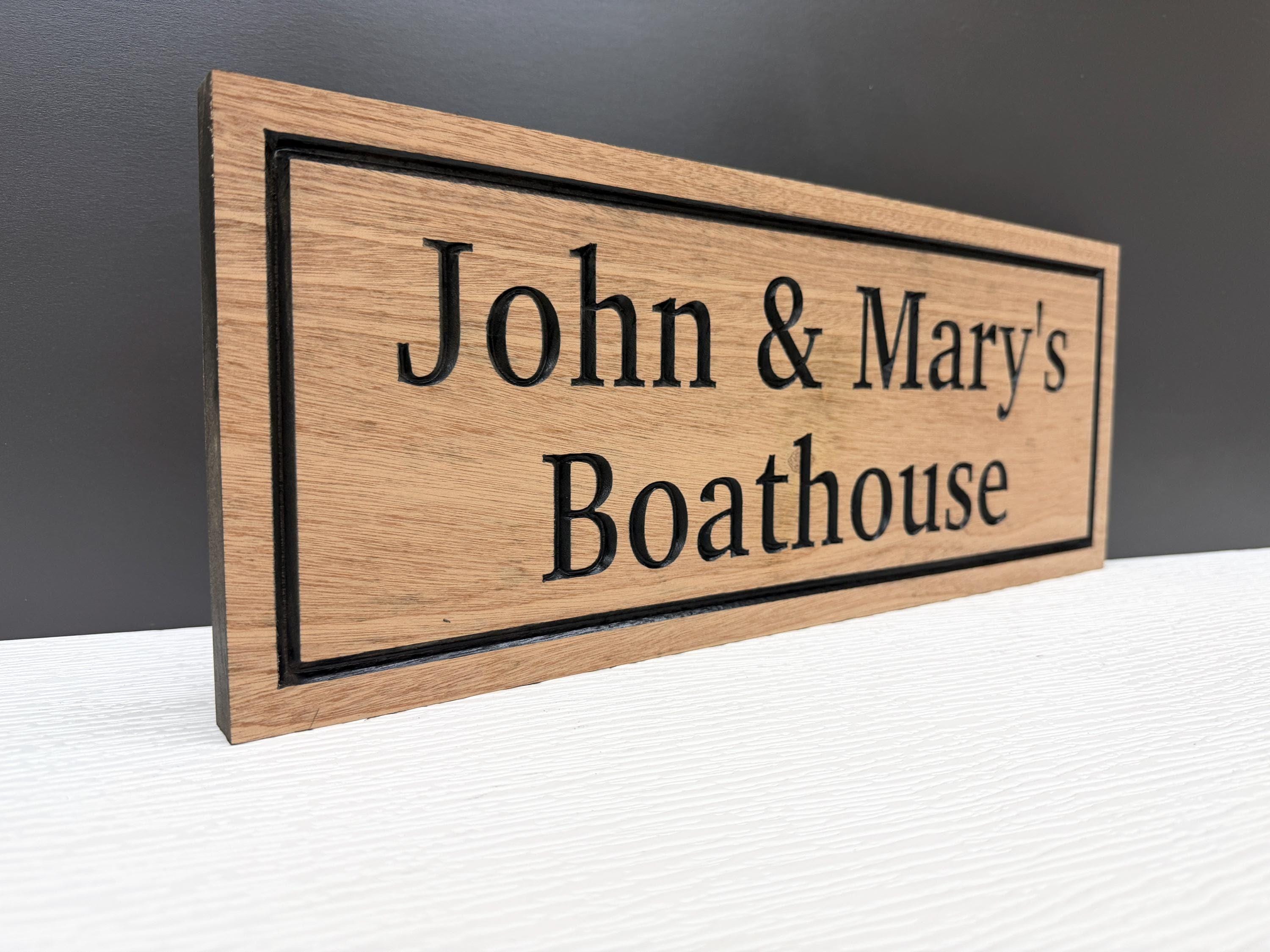 A wooden sign with the text "John & Mary's Boathouse" carved into it.