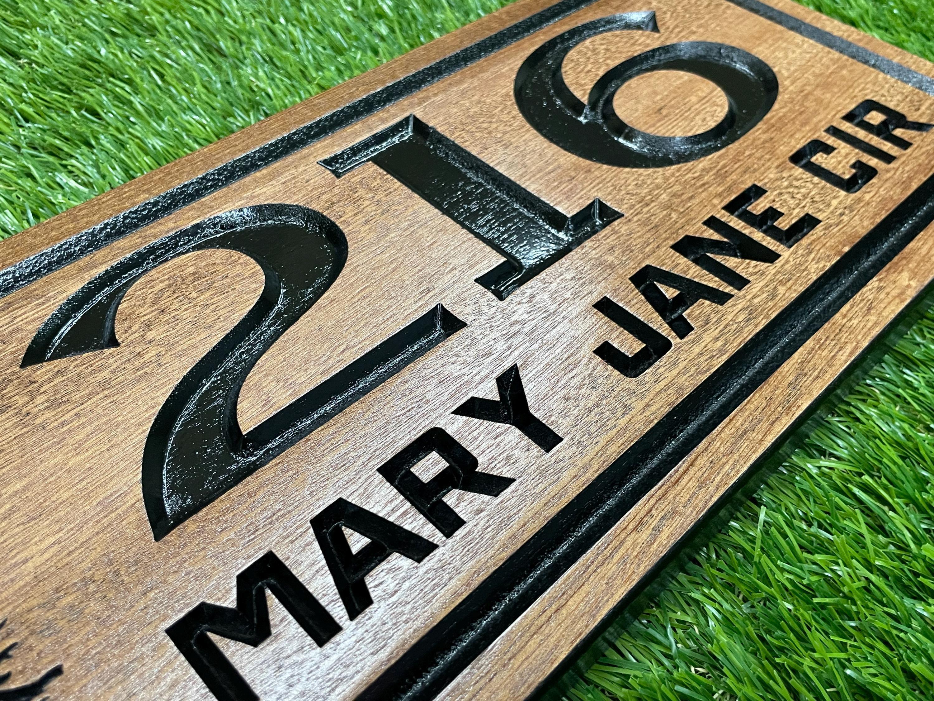 A wooden sign with the number "216" and the text "MARY JANE CIR" printed on it, placed on a grassy surface.
