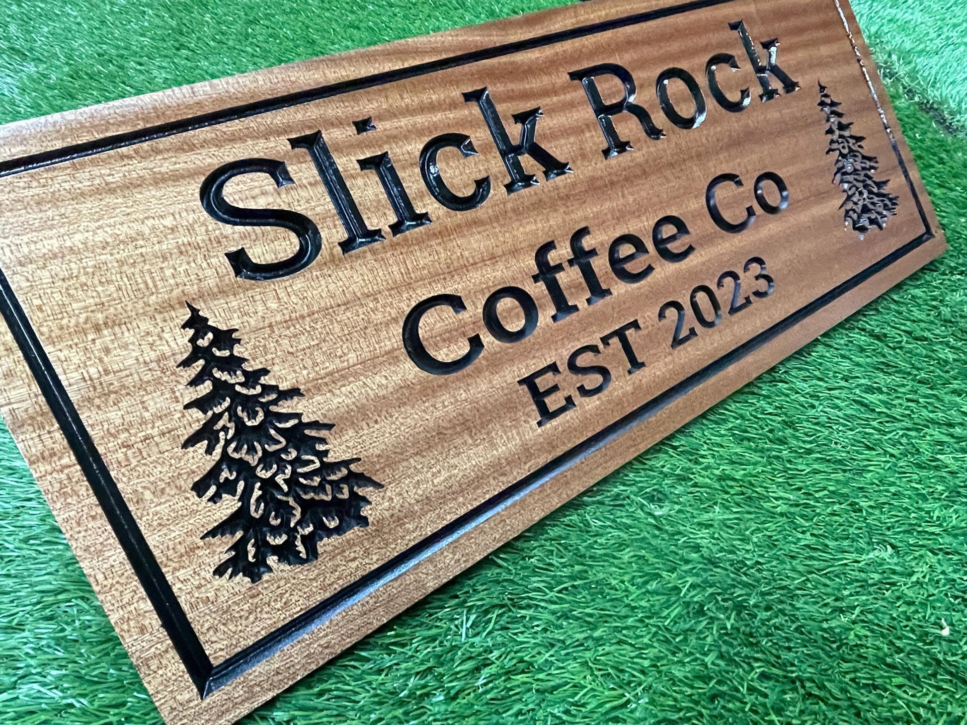 A wooden sign with the text "Slick Rock Coffee Co" carved into it, featuring a pine tree design.