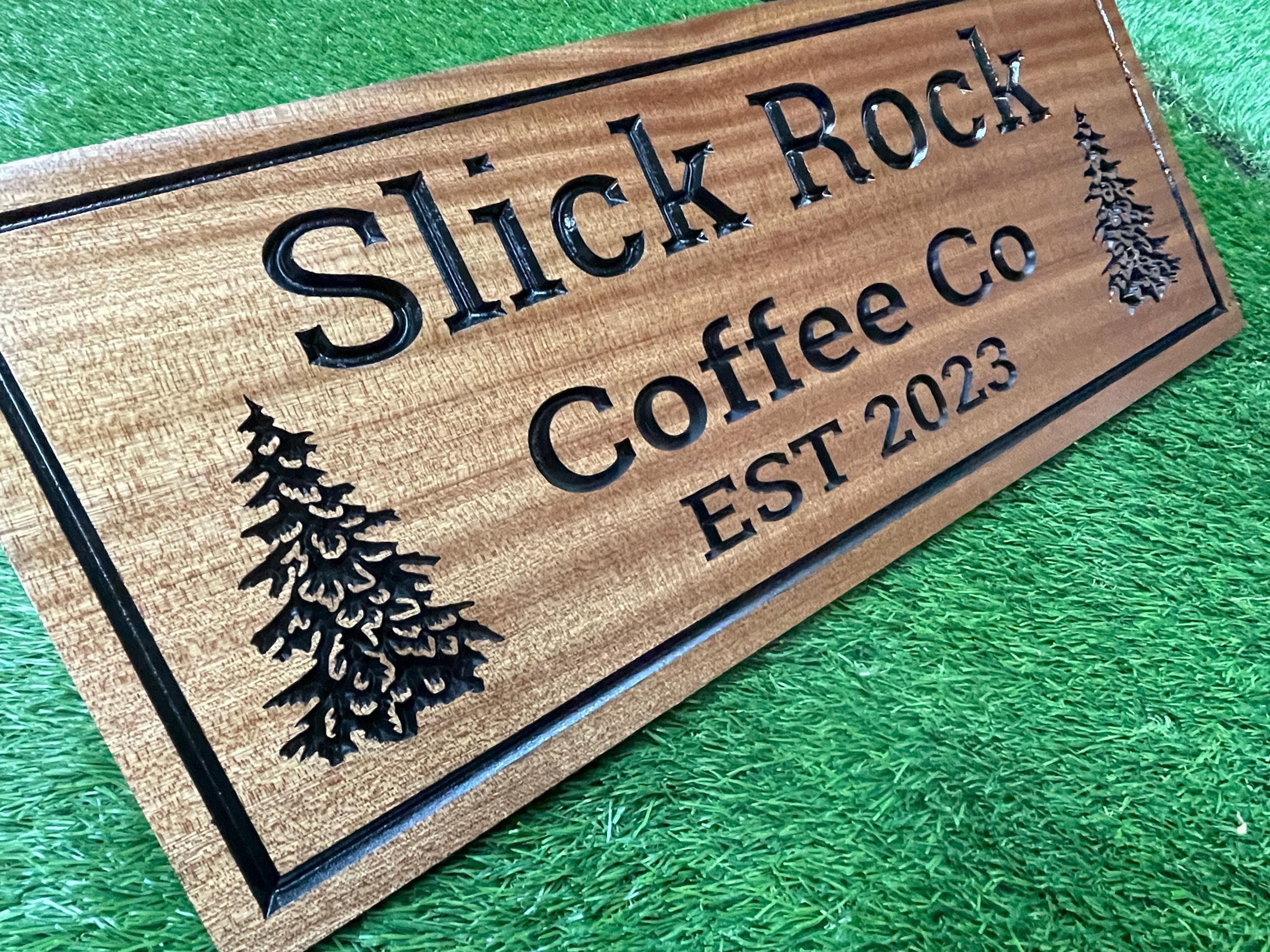A wooden sign with the text "Slick Rock Coffee Co" carved into it, featuring a pine tree design.