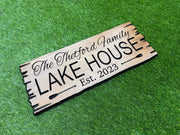 A wooden sign with the text "The Buttermilk House" and "Est. 2023" is lying on a grassy surface.