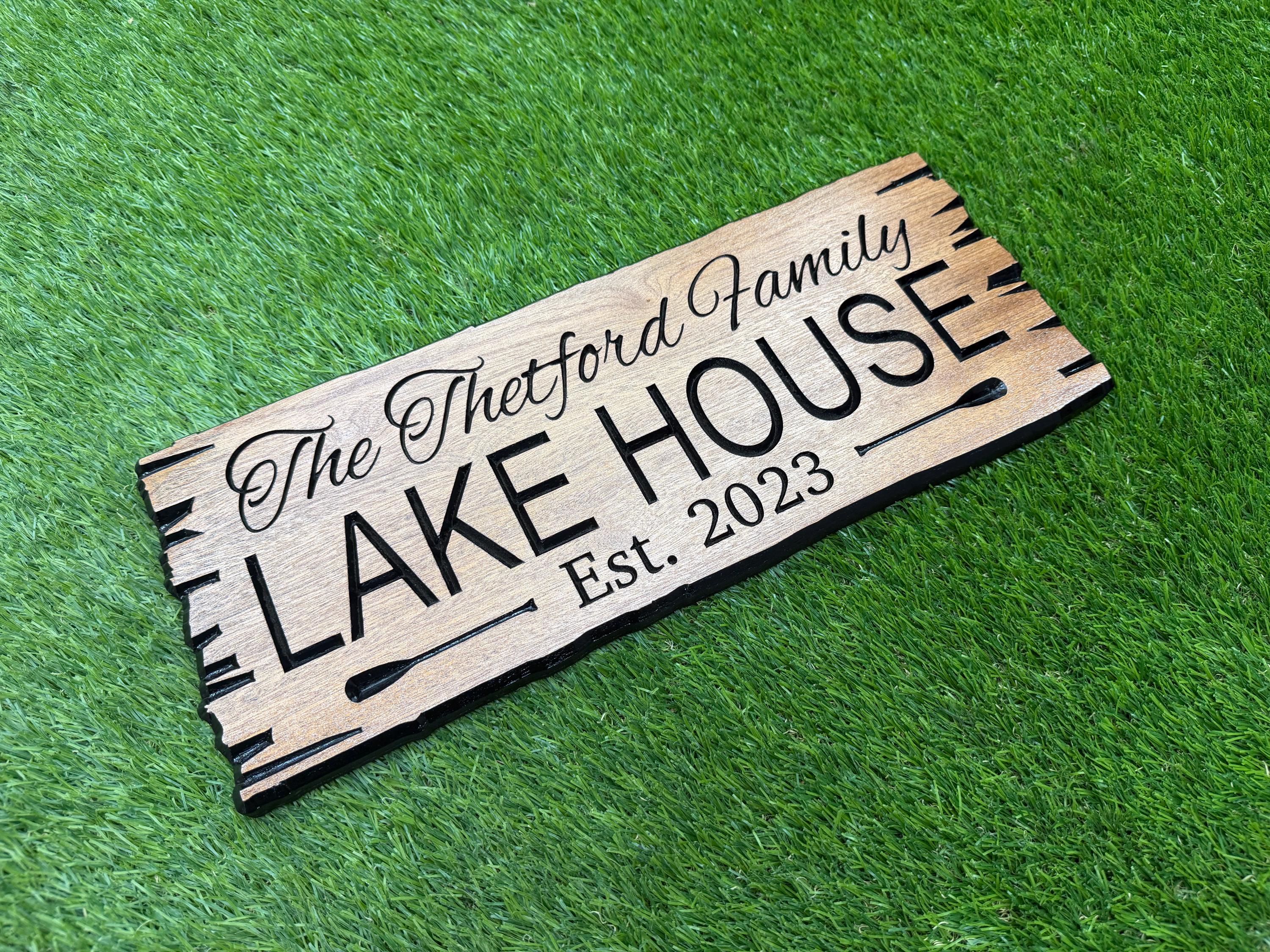A wooden sign with the text "The Buttermilk House" and "Est. 2023" is lying on a grassy surface.
