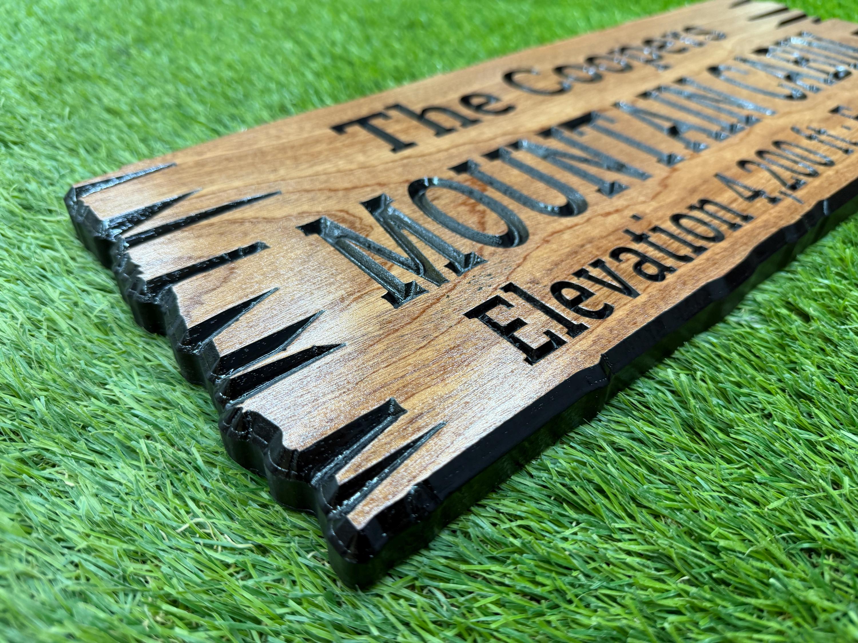 A wooden sign with text on it, placed on a grassy surface.