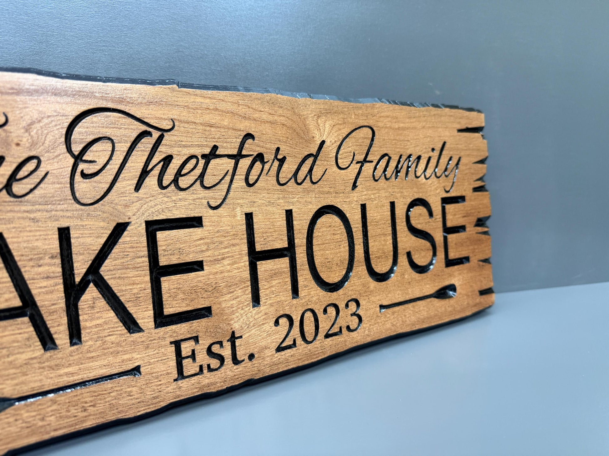 A wooden sign with the text "The Butts Family Lake House Est. 2023" carved into it.