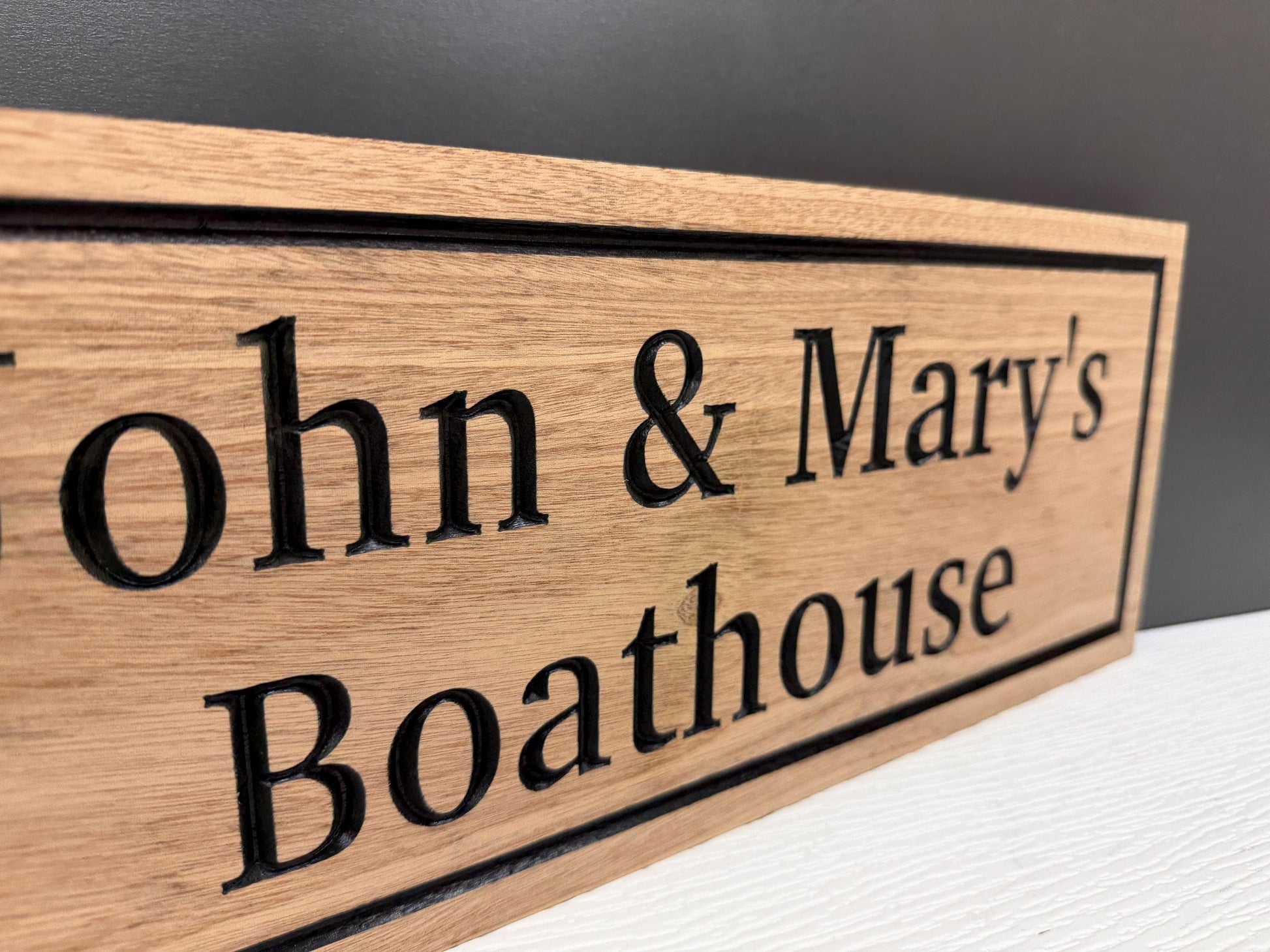 A wooden sign with the names "John & Mary's Boathouse" engraved on it.