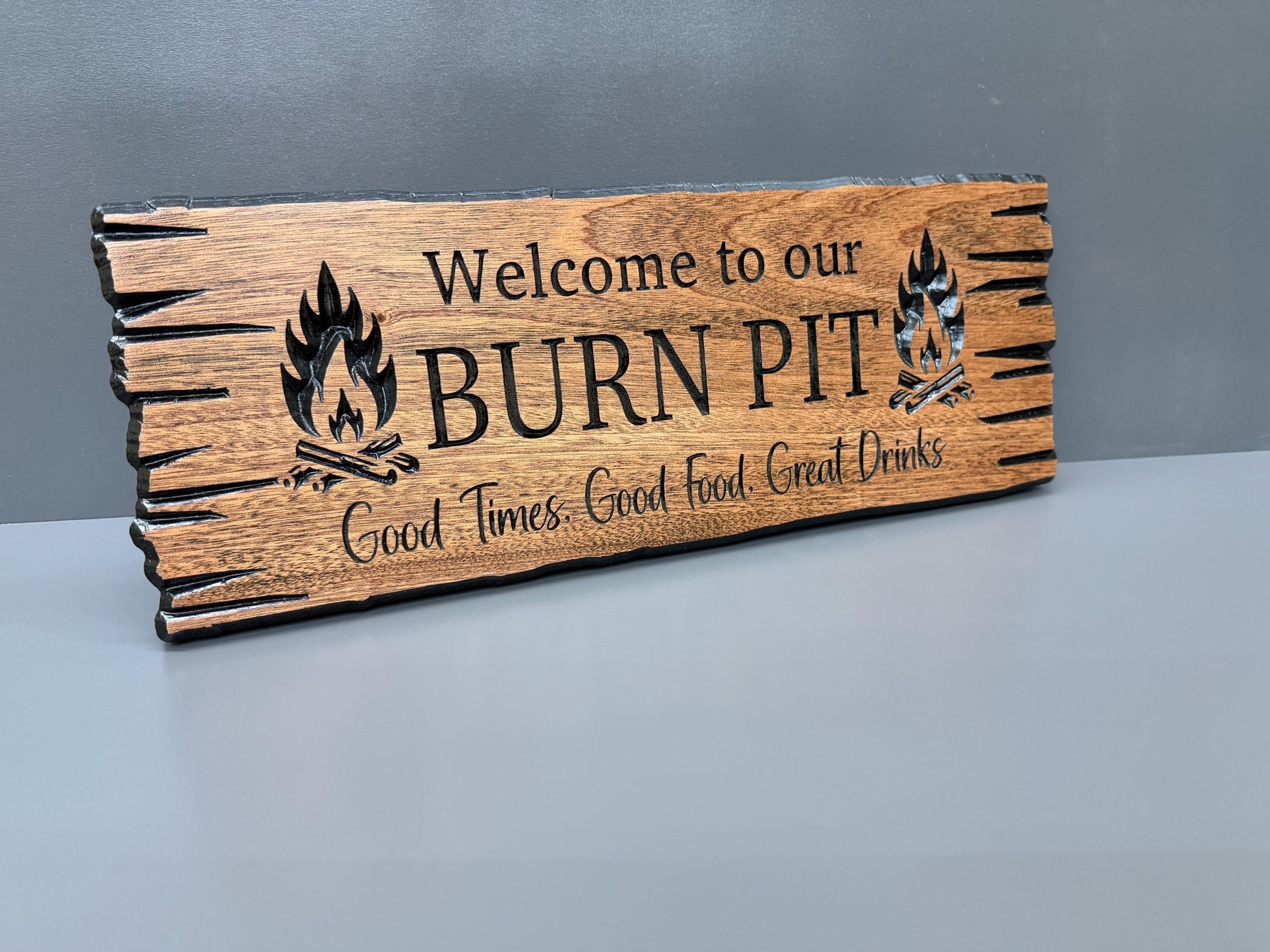 a wooden sign with the text "Welcome to our BURN PIT" and a graphic of a campfire.