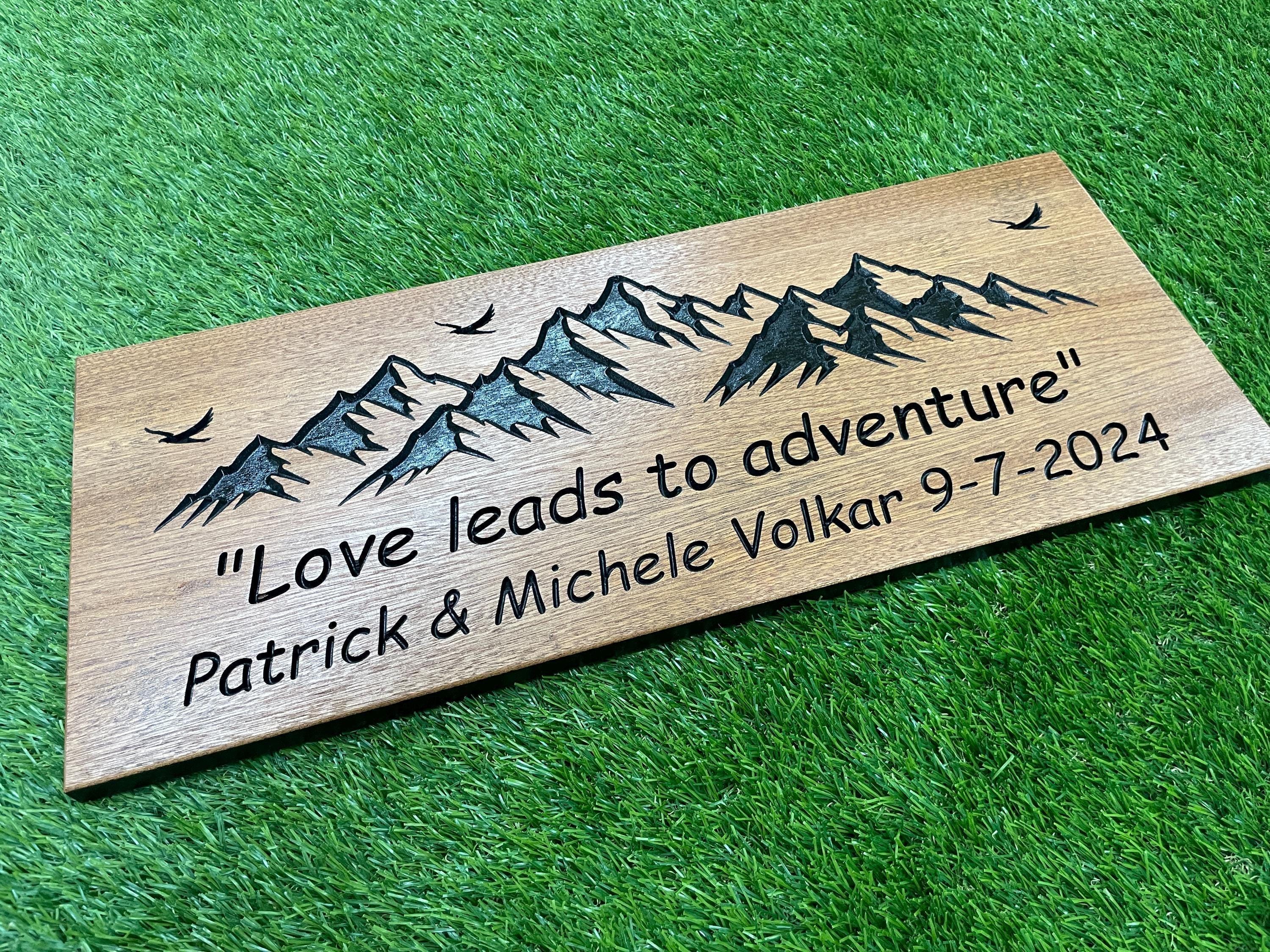 a wooden plaque with a mountain scene on it