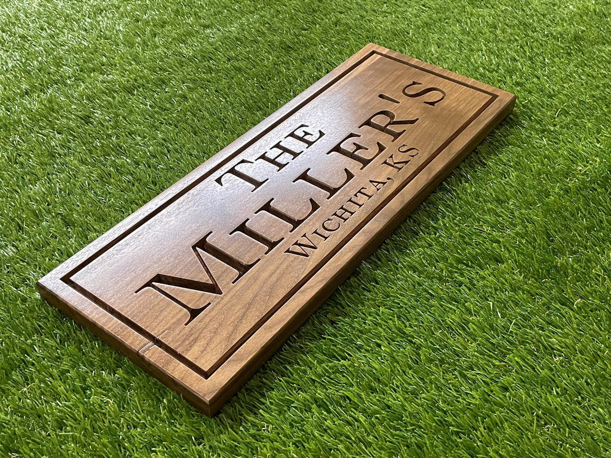 A wooden sign with the name "The Miller's" carved into it, placed on a grassy surface.