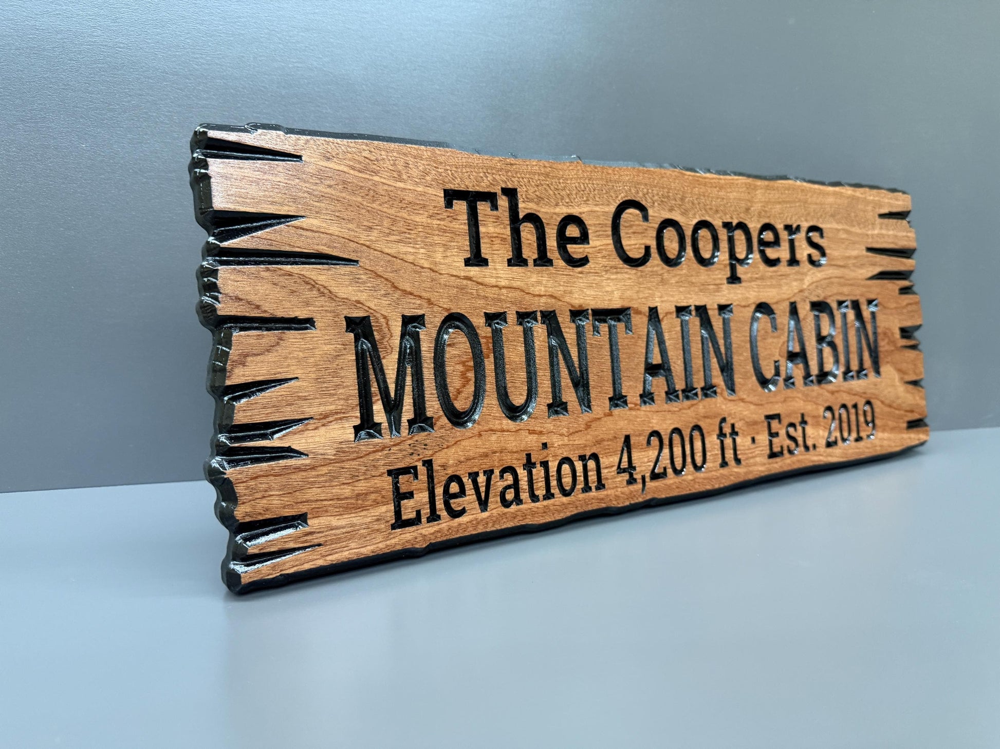 A wooden sign with the text "The Coopers Mountain Cabin Elevation 4,200 ft. Est. 2019" carved into it.