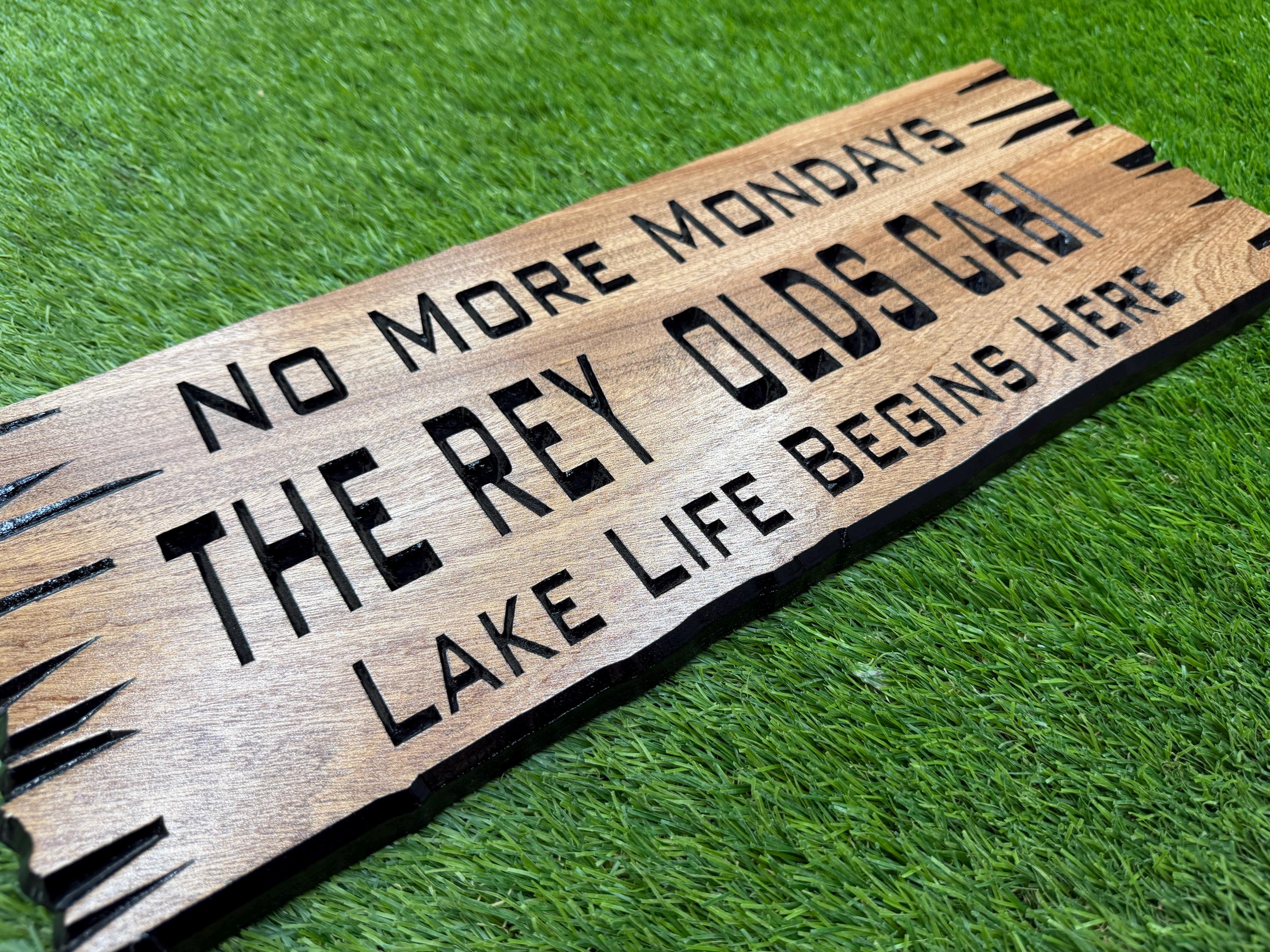 A wooden sign with text on it, placed on a grassy surface.